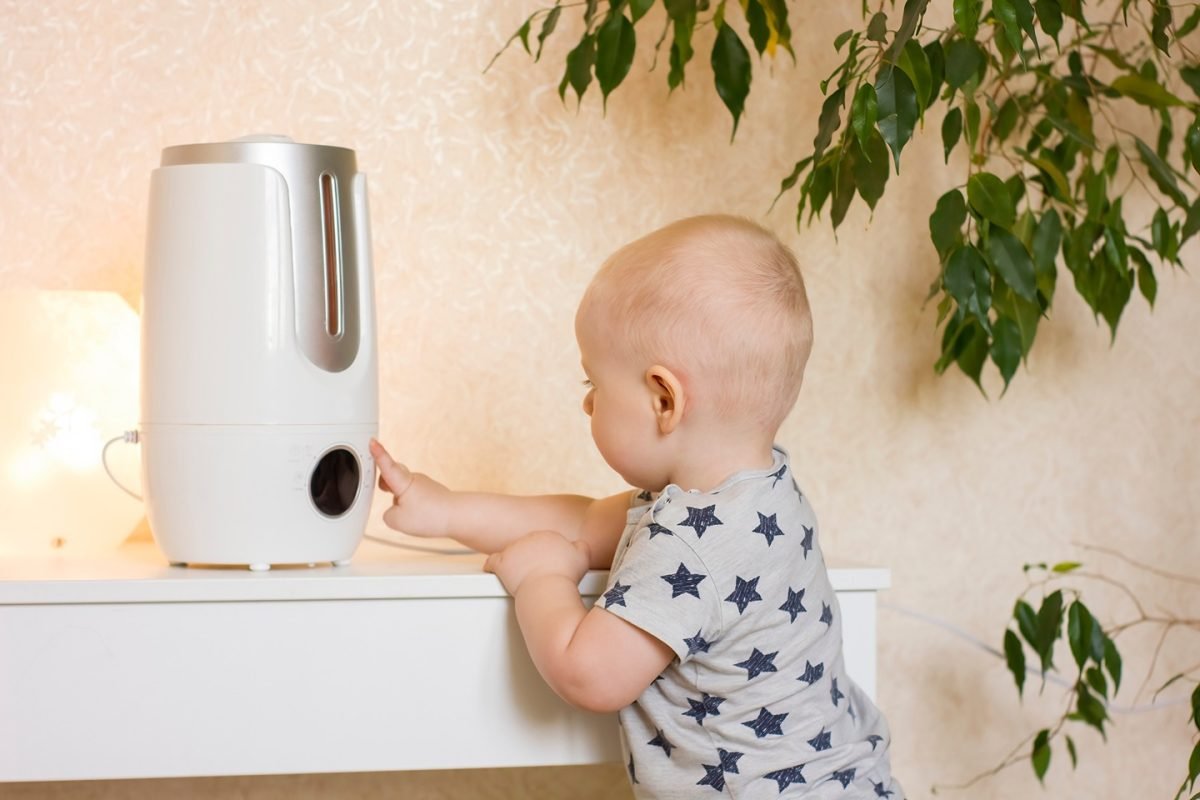 petit garçon-bébé-touche-le-bouton-sur-l'humidificateur d'air